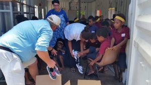 Mr Tonner of Vanuatu and team helping children find shoes that fit. 
