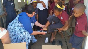 Mrs Sant visiting school in Vanuatu and helping children try on new shoes. 